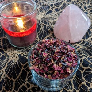 love herbal blend with red candle burning and large rose quartz crystal