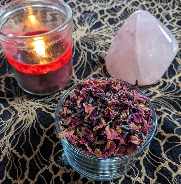 love herbal blend with red candle burning and large rose quartz crystal